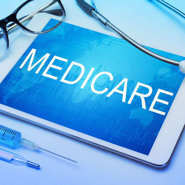 Medicare word on tablet screen with medical equipment on background